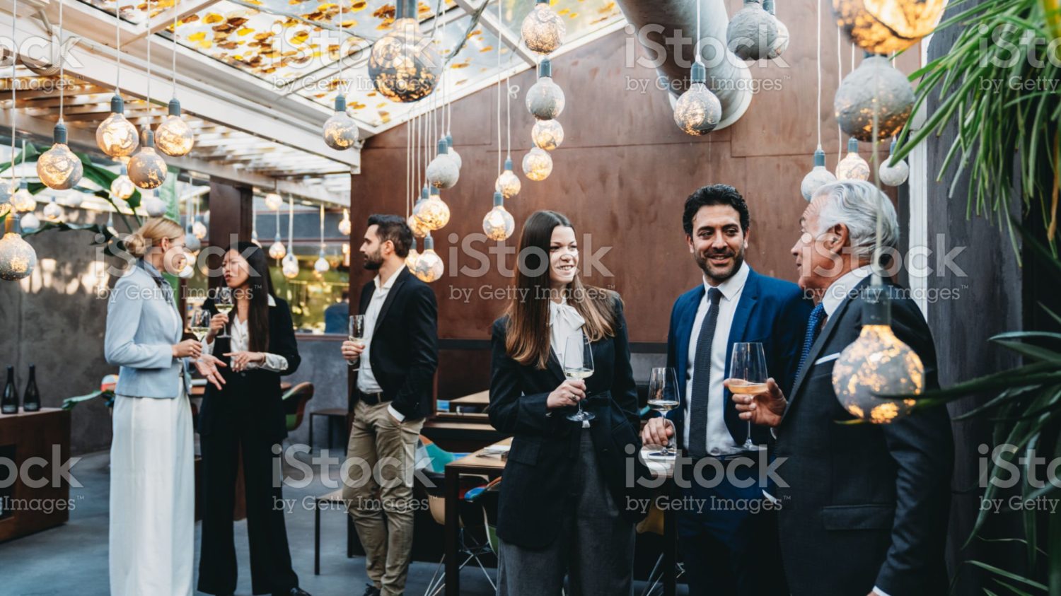 Business people are talking together during a teambuilding event in a luxury restaurant. They are drinking wine, waiting for the dinner.